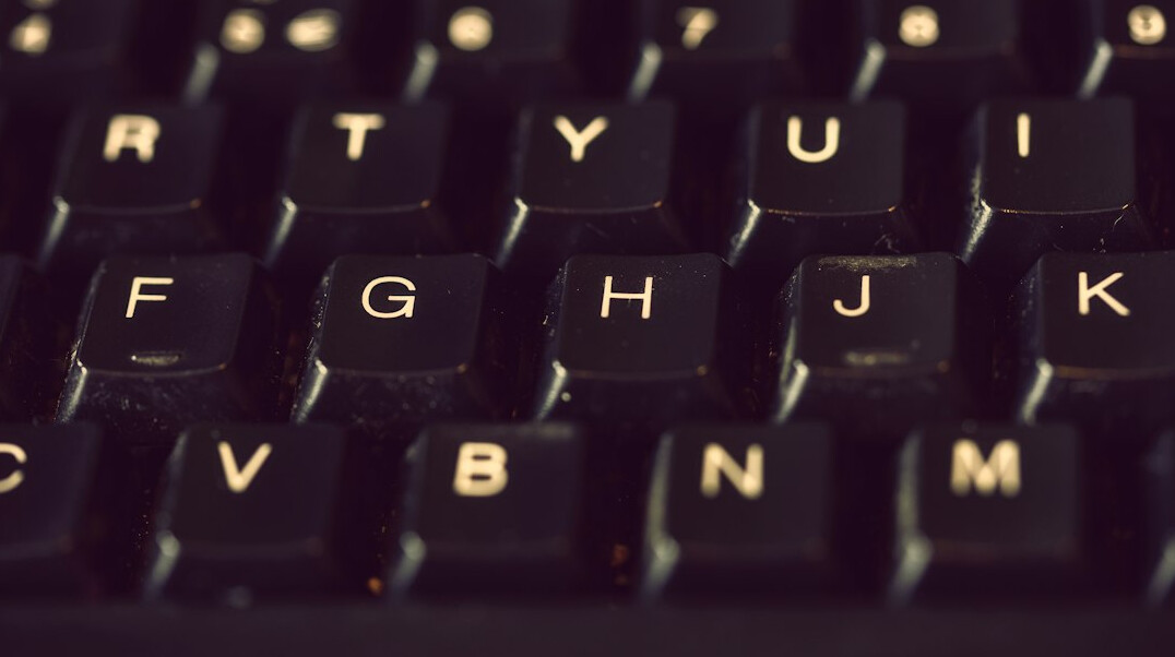 Close up of hands typing code on a laptop keyboard